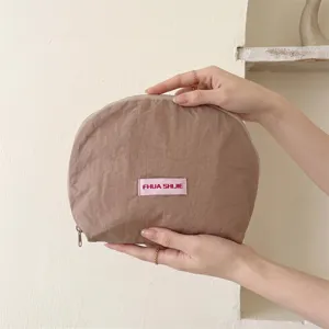 Detailweergave van een lichte bruine halve cirkel make-uptas met roze label