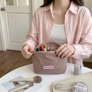 Detailopname van een roze Koreaanse make-uptas met cosmetica op een witte tafel