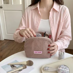 Detailopname van de roze halfronde make-uptas die de ruime opslagcapaciteit toont.