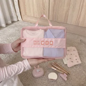 Detailed view of a pink mesh travel clothing organizer bag held by hands on a soft carpet.