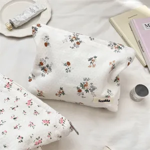 Dettaglio di una trousse per il trucco trapuntata a fiori su un letto minimalista