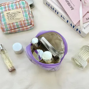Close-up of open purple quilted mini pouch showing various cosmetic items inside.