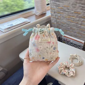 Close-up view of a floral drawstring fabric storage bag holding earphones in a travel setting