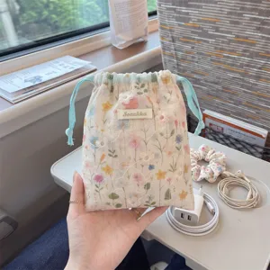 Detail shot of a floral drawstring storage bag held by hand in a travel setting