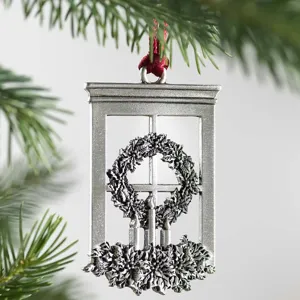 Detailed close-up of a silver window-shaped Christmas tree ornament with wreath and candles.