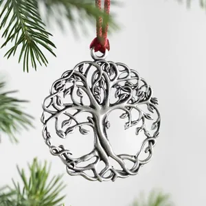 Close-up detail of silver metal tree of life Christmas ornament with red ribbon hanging loop.