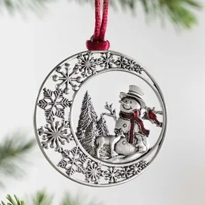 Close-up detail of a silver-tone metal Christmas tree ornament with intricate winter theme.