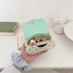 Vue intérieure d'une mini trousse à maquillage à pois contenant des cosmétiques et pots