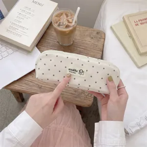 Dettaglio di un simpatico astuccio in tessuto a pois in stile coreano tenuto in mano in un caffè