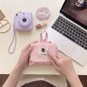 Gros plan détaillé d'une mini pochette rose à pois tenue en main avec un motif de chat mignon