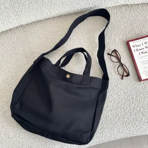Vista detallada del bolso tote de lona negra con correa ancha para el hombro
