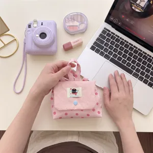 Détail en gros plan d'une mini pochette rose à pois tenue à la main sur un bureau de travail net