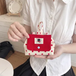 Petite pochette à pois de style coréen pour pièces et clés tenue à la main par un modèle
