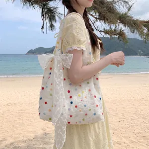 Detail mit bunten Polka-Dot-Stickereien und Spitzenschleife an einer Canvas-Tasche