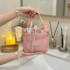 Nahaufnahme einer rosa Kulturbeutel-Netztasche im Dopamin-Stil mit Reiseutensilien im Badezimmer