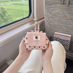 Détail d'une petite pochette rose à pois portable tenue à la main lors d'un voyage en train