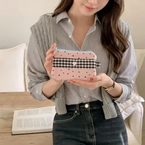 Close-up of a stylish pink star pattern pencil case with heart detail held by a model in a cafe