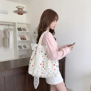 Detailansicht einer weißen Polka-Dot-Einkaufstasche mit großer Spitzenschleife