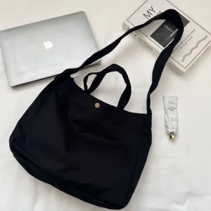 Vista superior de un espacioso bolso tote de lona negra con portátil y libros