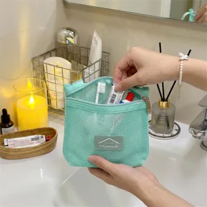 Nahaufnahme einer mintgrünen Netztasche für Toilettenartikel, die mit Zubehör befüllt wird