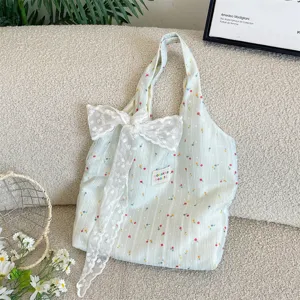 Vista detallada del bolso tote floral a rayas con un elegante lazo de encaje blanco