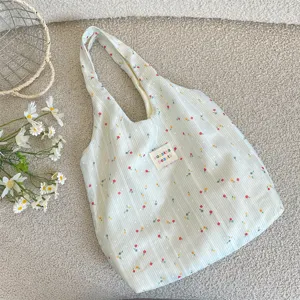 Primer plano detallado de un bolso tote verde claro a rayas florales con etiqueta de tela