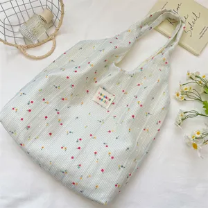 Primer plano de un bolso tote verde claro con rayas verticales y estampados florales.