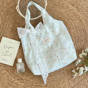 Detalle del bolso de tela verde claro con flores y un gran lazo de encaje blanco suave.