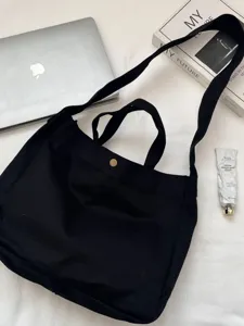Bolso tote minimalista de lona negra con correa ancha para estudiantes.