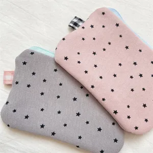 Detail of grey and pink fabric pencil cases with black star patterns and checkered tabs