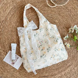 Detailansicht der cremefarbenen Tragetasche mit Tulpenmuster und großer weißer Spitzenschleife