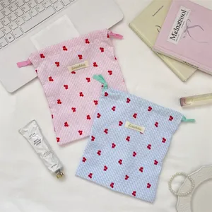 Vista de detalle de bolsas con cordón a cuadros con bordados de cerezas rojas.