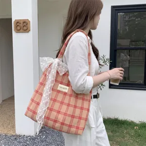 Borsa tote in tela a quadretti arancioni con fiocco in pizzo bianco portata a spalla
