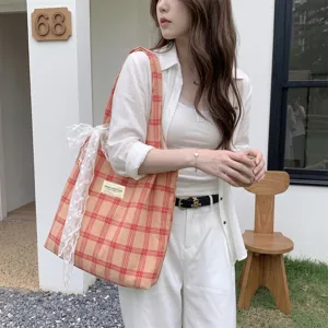 Dettaglio borsa shopper a quadri con elegante fiocco in pizzo bianco per uso quotidiano