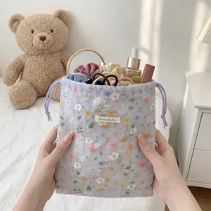 Close-up of a floral drawstring storage pouch holding cosmetics and hair accessories