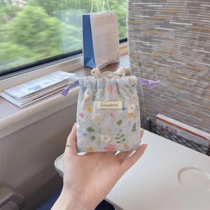 Close-up view of a floral drawstring storage pouch featuring delicate white embroidery details
