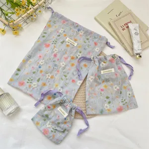 Three-piece set of light blue floral drawstring storage bags with elegant purple ties.