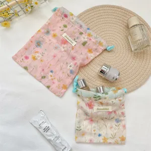 Detail of floral embroidered drawstring pouches for makeup and travel storage.