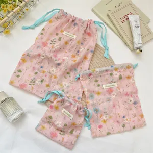 Set of three sizes of pink drawstring bags with floral embroidery and blue ties