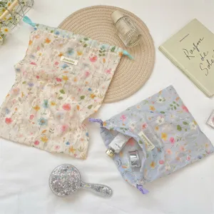 Detail view of colorful floral embroidered drawstring pouches for cosmetics storage