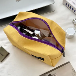 Grote gele canvas cosmetische tas met paarse rits open met huidverzorgingsitems