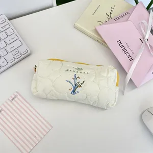 Estuche acolchado de estilo literario con delicado bordado de flores en escritorio.