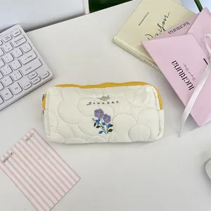 Primer plano de un estuche acolchado blanco con delicado bordado floral morado