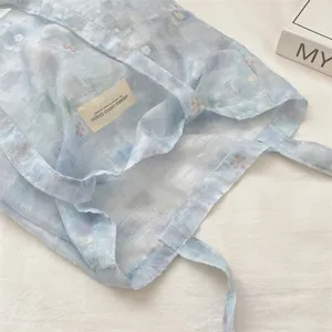 Macro view of ice blue floral lace tote bag detailing sheer texture and fabric label