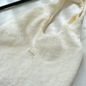 Close-up of cream cherry blossom embroidery detail on Korean style textured fabric tote bag.