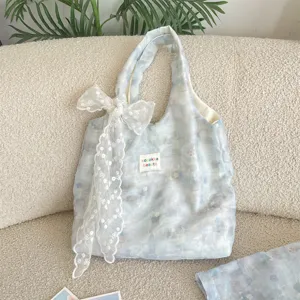 Detailed macro view of the delicate lace bow and marbled floral print on blue tote bag