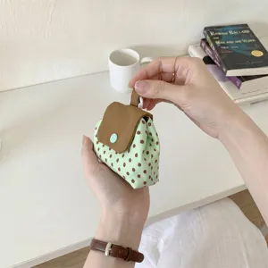 Handansicht einer kleinen gepunkteten Tasche mit Druckknopf für Kopfhörer oder Lippenstift