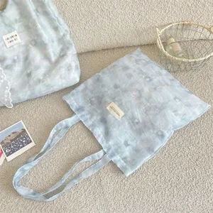 Detailed view of ice blue tie-dye floral tote bag with lace bow decoration