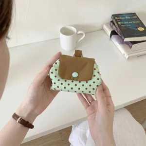 Nahaufnahme einer mintgrünen gepunkteten Tasche mit brauner Klappe und Druckknopf
