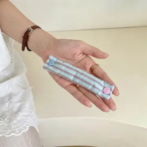 Dettaglio dell'organizzatore per cavi in tessuto a righe con bottone a cuore blu